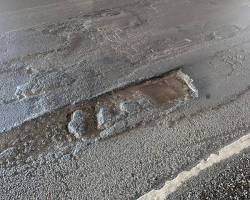 A deep asphalt pothole road defect on a California highway illustrating when can you sue Caltrans after a crash caused by a road defect.